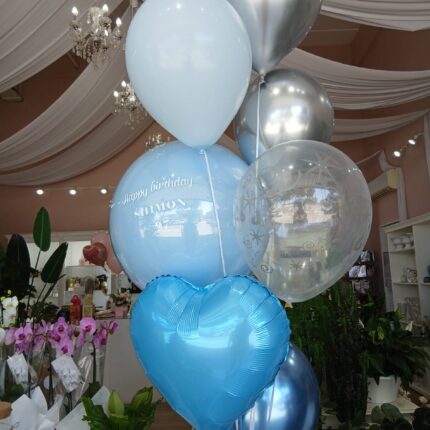 🎈 זר בלונים חגיגי בכחול ותכלת – מתנה מושלמת לכל חגיגה 🎈 בתמונה מוצג זר בלונים בעיצוב יוקרתי בגווני תכלת, כחול וכסף, הכולל שילוב של בלוני הליום בגדלים וצורות שונות – בלון לב כחול מבריק, בלונים שקופים עם הדפסים עדינים, בלוני פנינה כסופים ובלון תכלת עם הקדשה אישית: Happy Birthday Shimon – עיצוב בהתאמה אישית שמשדר השקעה וסטייל.